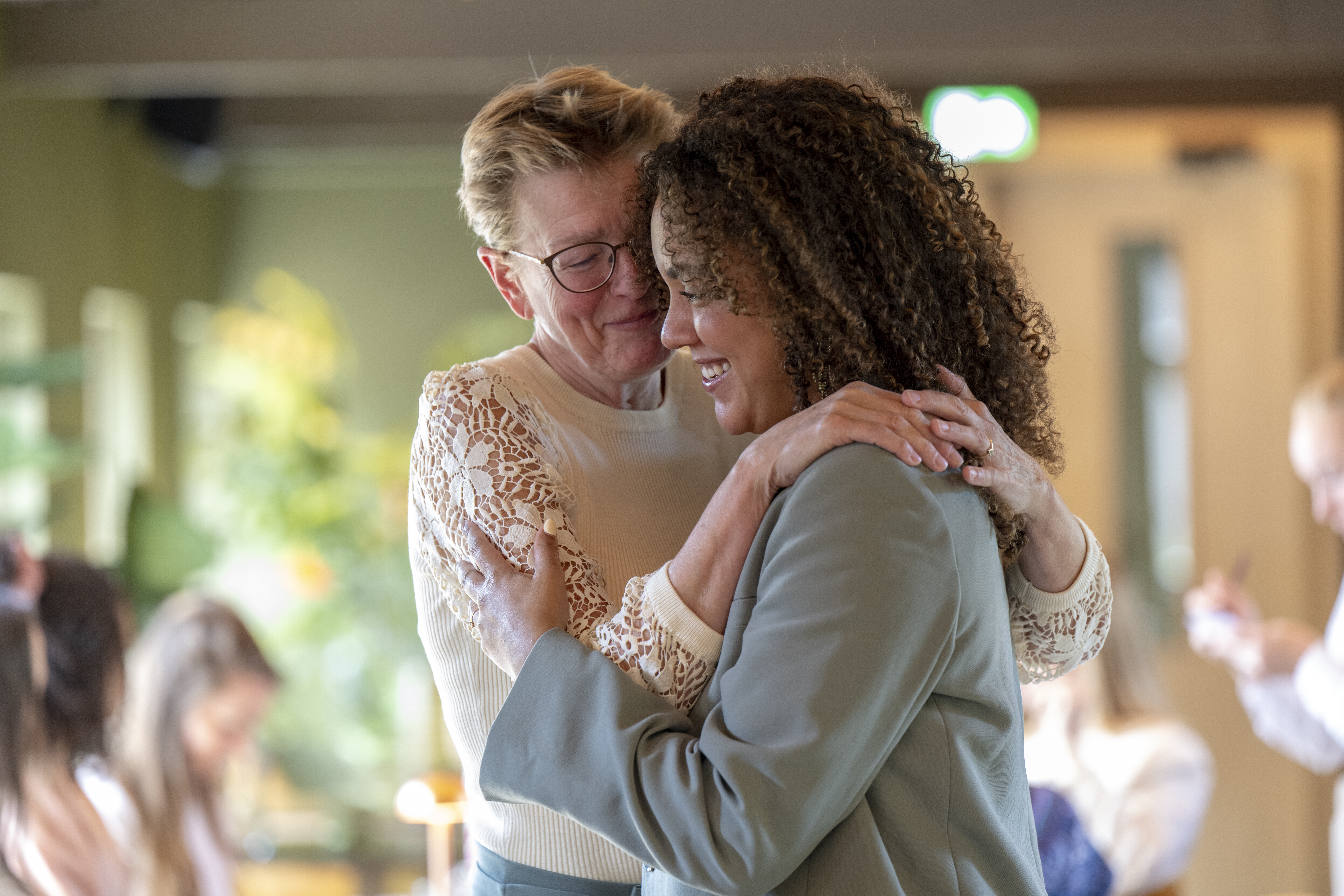 Joyful embrace between two women sharing a moment of happiness and affection indoors.