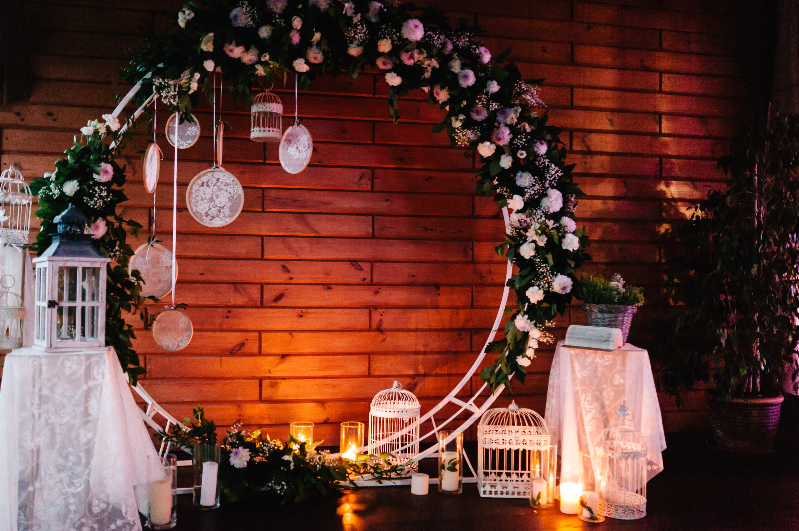 Night wedding ceremony with a vintage candles. Arch for wedding ceremony a is decorated with white flowers and greens, greenery. Wedding decoration on boho style: Dream catchers.
