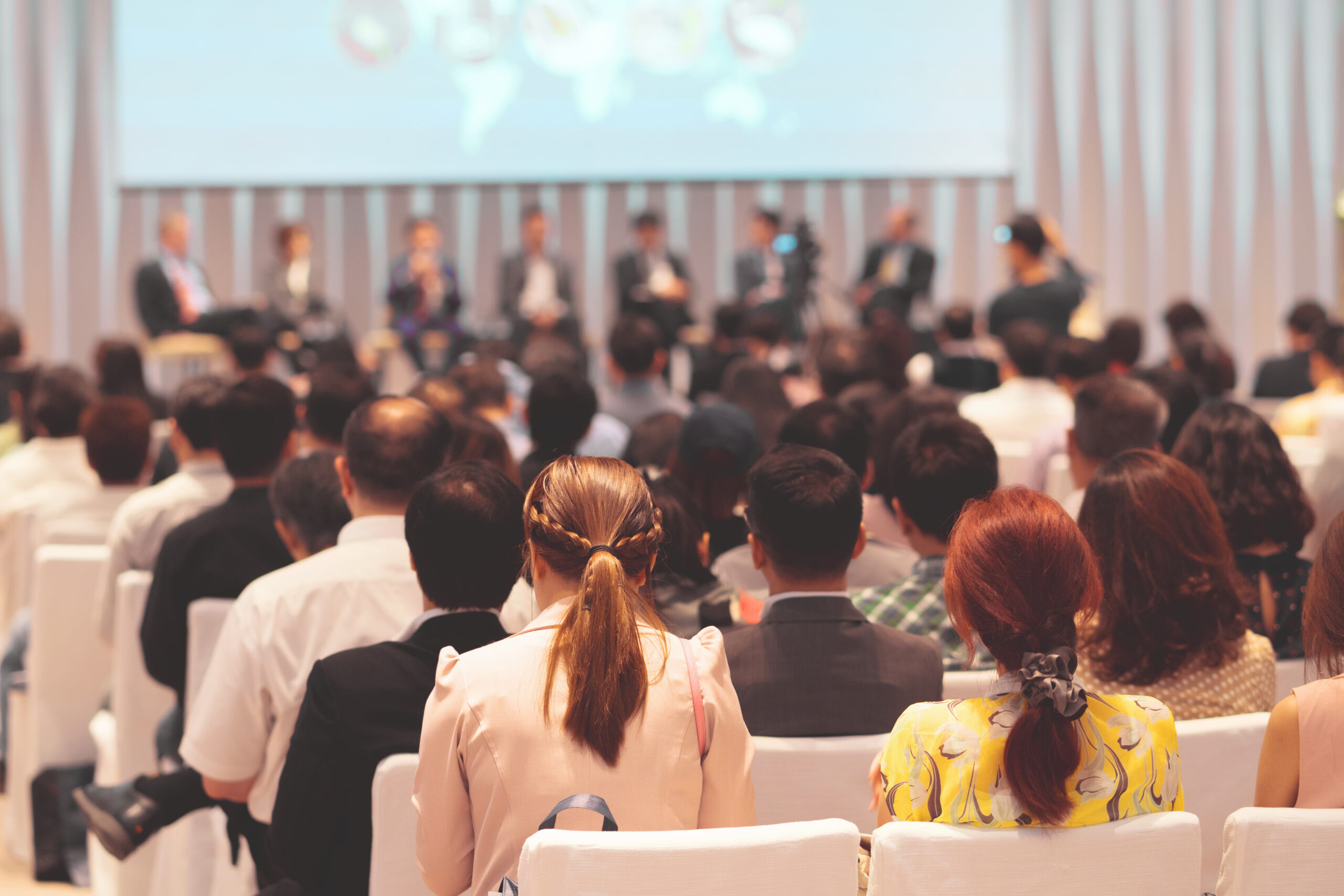 Rear view of Audience in the conference hall or seminar meeting which have Speakers on the stage